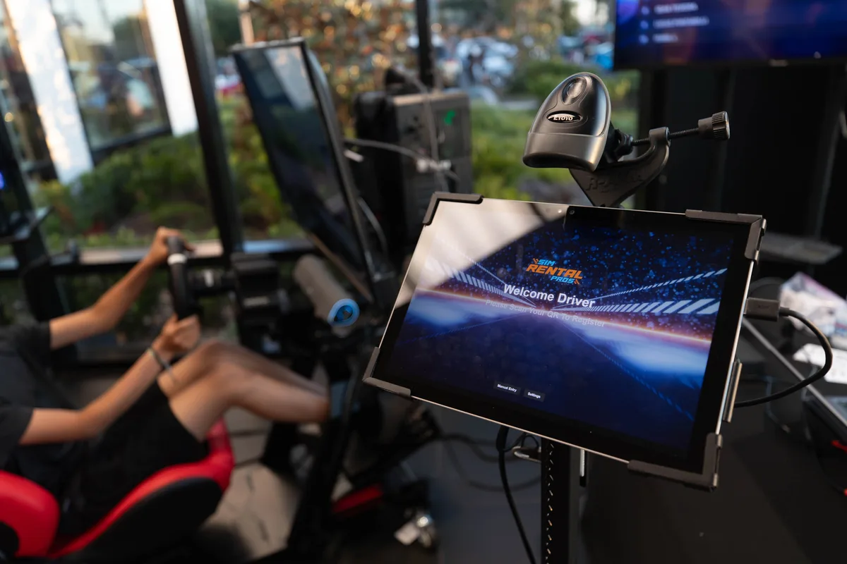 Guest experiencing a professional racing simulator with registration kiosk